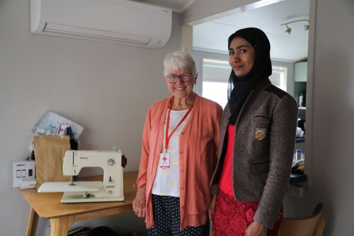Two women standing next a sewing machine