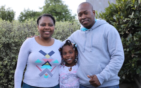 Two adults and a child standing together.