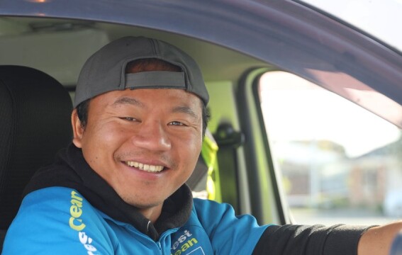 A smiling man sitting behind the steering wheel of a car.