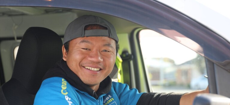 A smiling man sitting behind the steering wheel of a car.