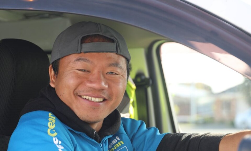 A smiling man sitting behind the steering wheel of a car.