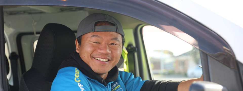 A smiling man sitting behind the steering wheel of a car.