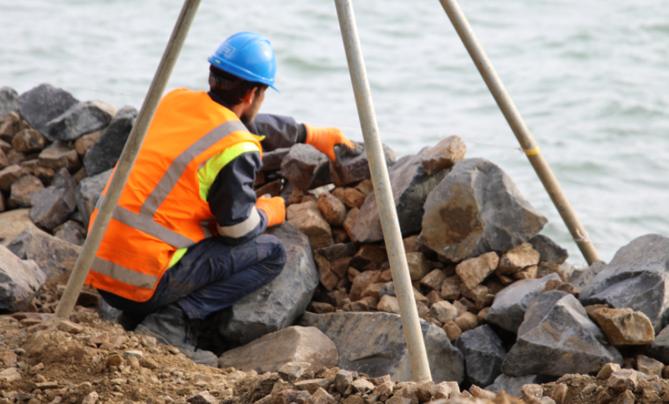 A man working on a seawall. 