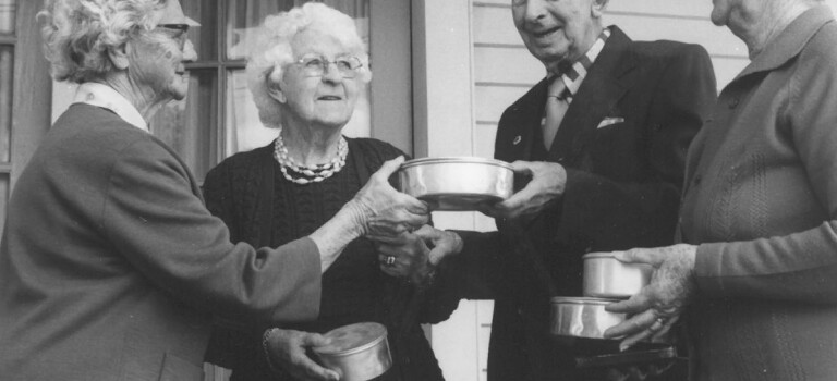 Three older women and an older man with packaged meals.