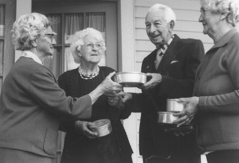 Three older women and an older man with packaged meals.