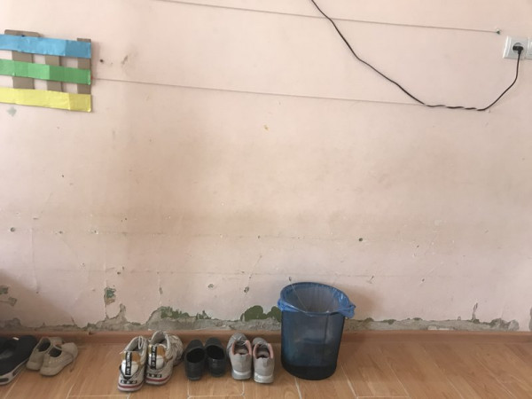 Shoes and a bucket next to an internal wall. 