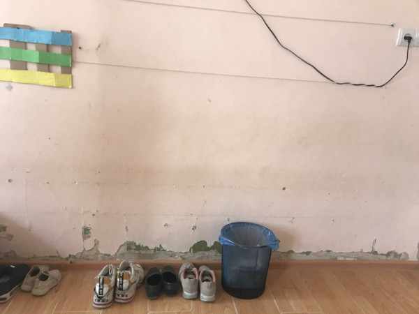 Shoes and a bucket next to an internal wall.