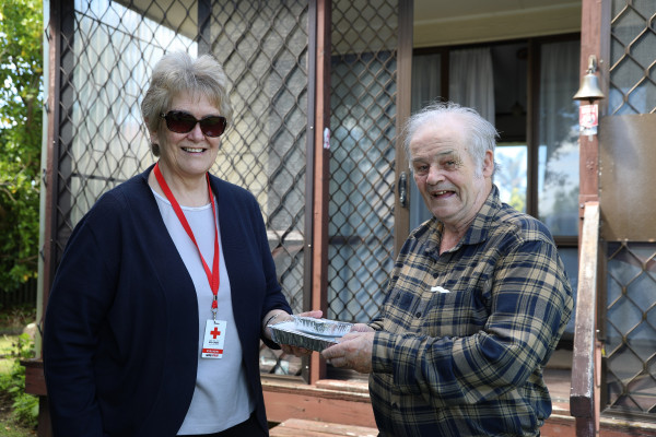 A woman handing a man a packaged meal. 