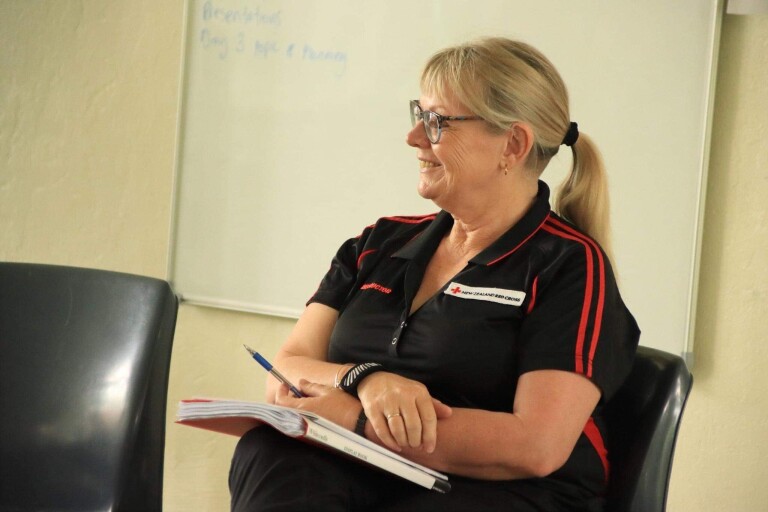 A blonde woman sitting and smiling.