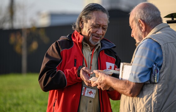 A man handing another man a packaged meal.