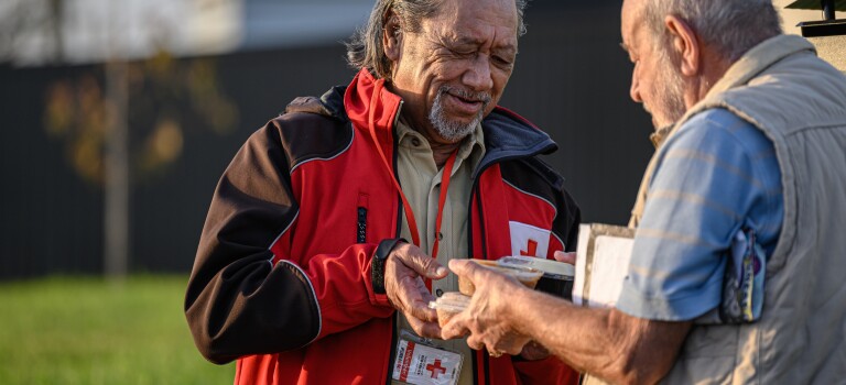 A man handing another man a packaged meal.