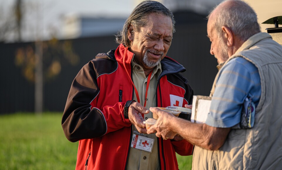 A man handing another man a packaged meal.