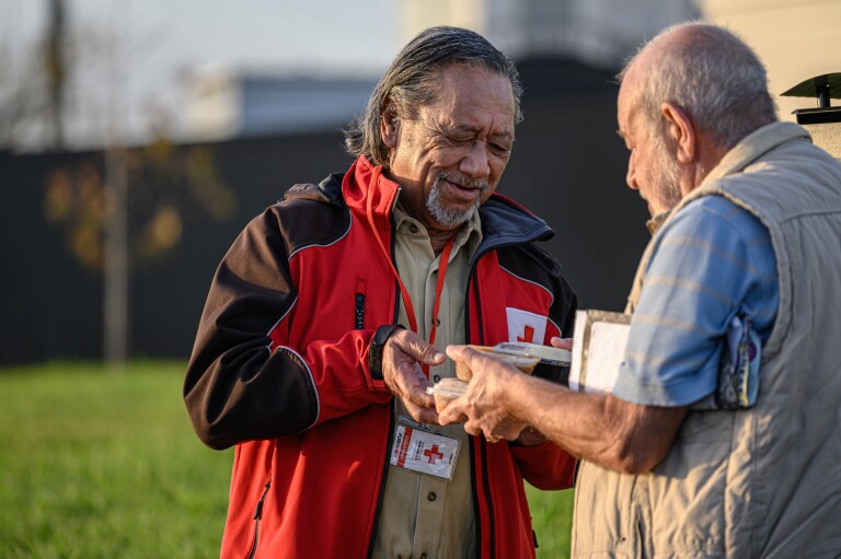 A man handing another man a packaged meal.