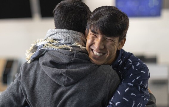 A man hugging someone and smiling.