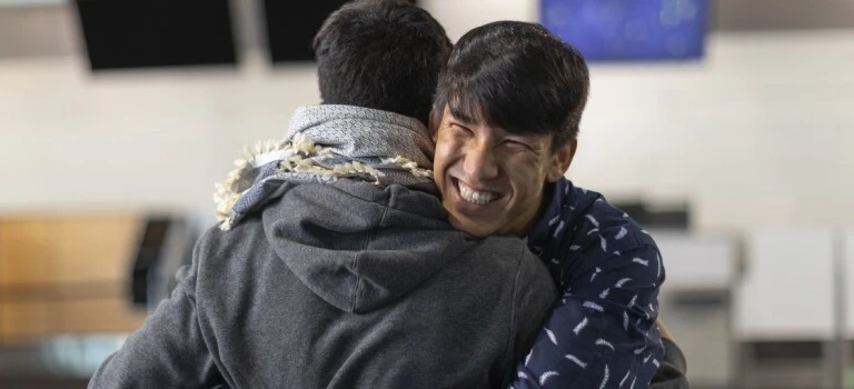 A man hugging someone and smiling.