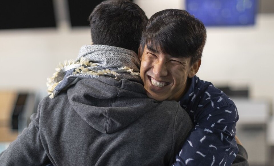 A man hugging someone and smiling.