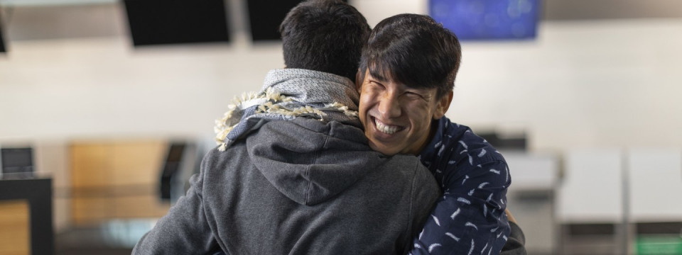 A man hugging someone and smiling.