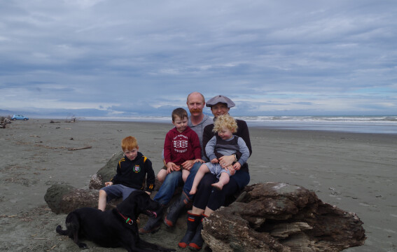A family of five sitting on a beach.