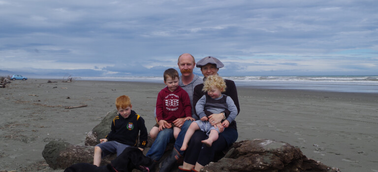 A family of five sitting on a beach.