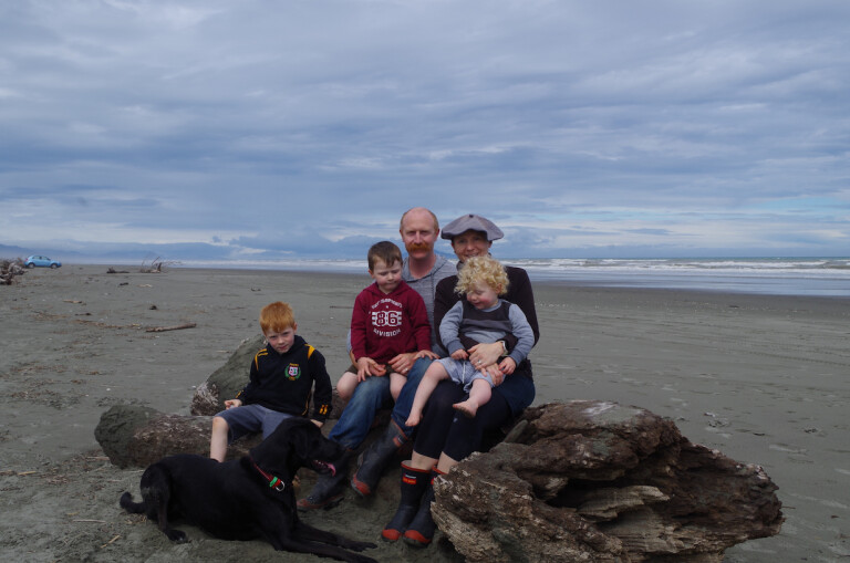 A family of five sitting on a beach.