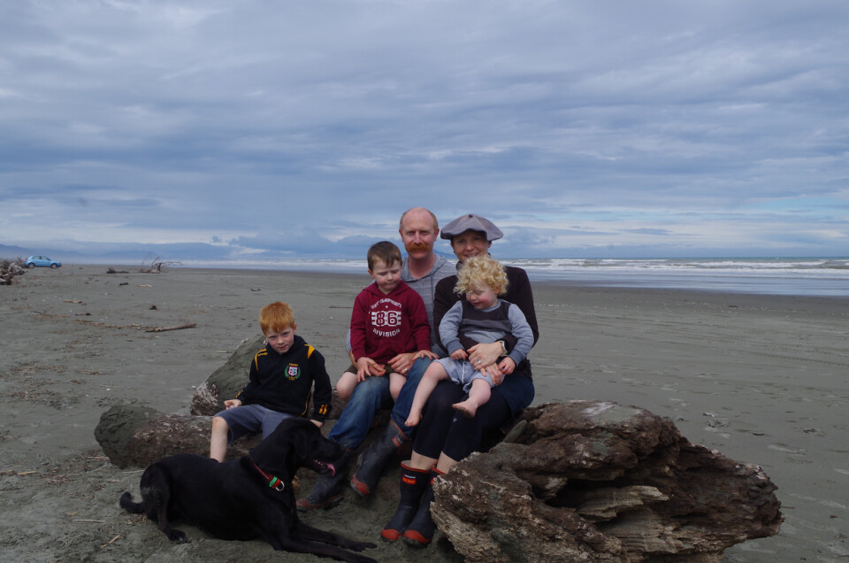 A family of five sitting on a beach.