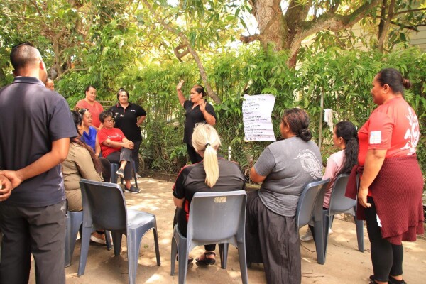 Group of people sitting together at a presentation outside.