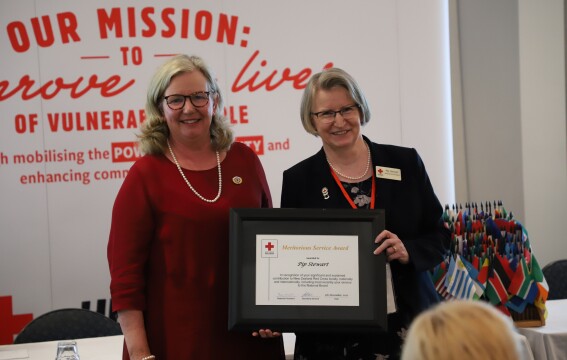 Two women standing together, one is holding an award