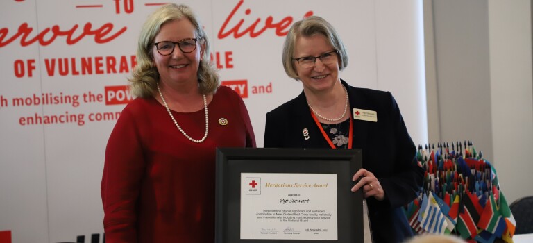 Two women standing together, one is holding an award