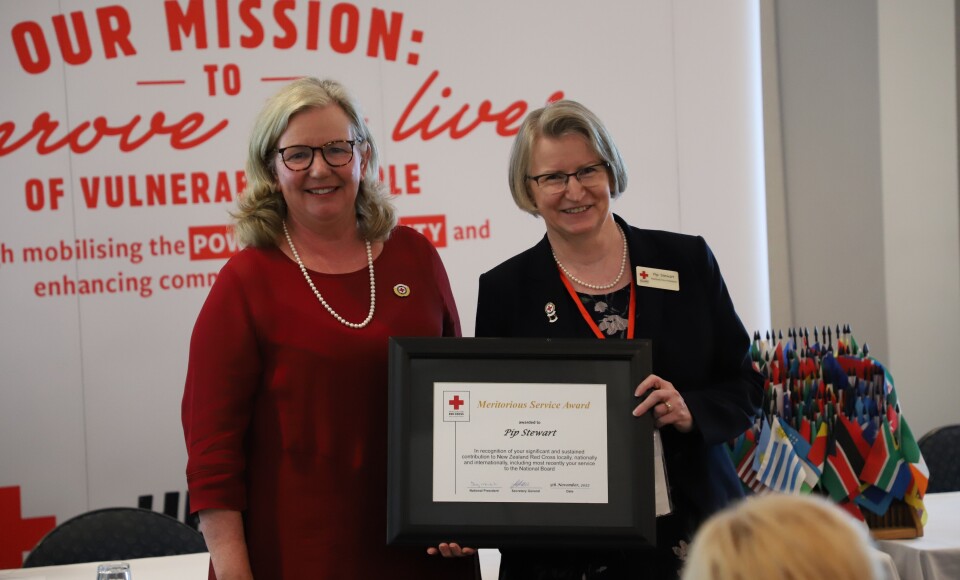 Two women standing together, one is holding an award