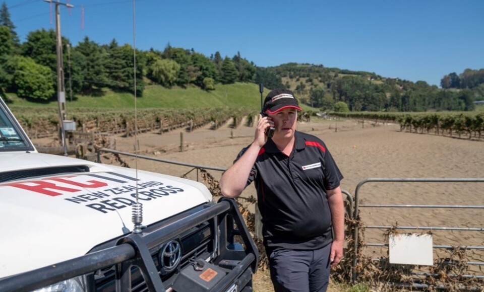 A man standing next to a vehicle using a satellite phone 