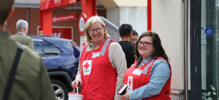 Two women standing together wearing fundraising jackets.