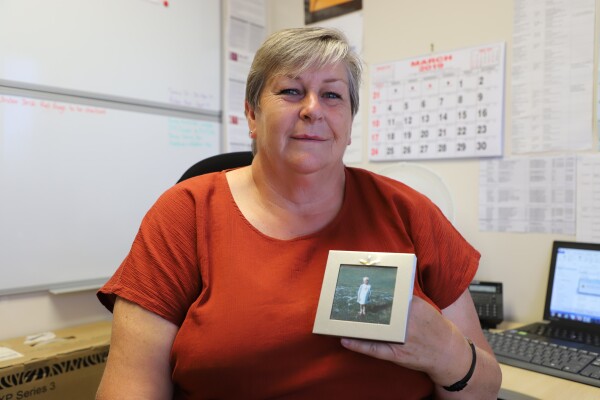 A woman holding a photograph of herself as a child