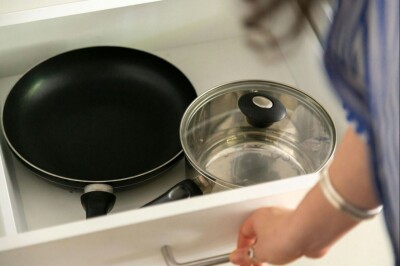 Women opening a draw containing pots and pans