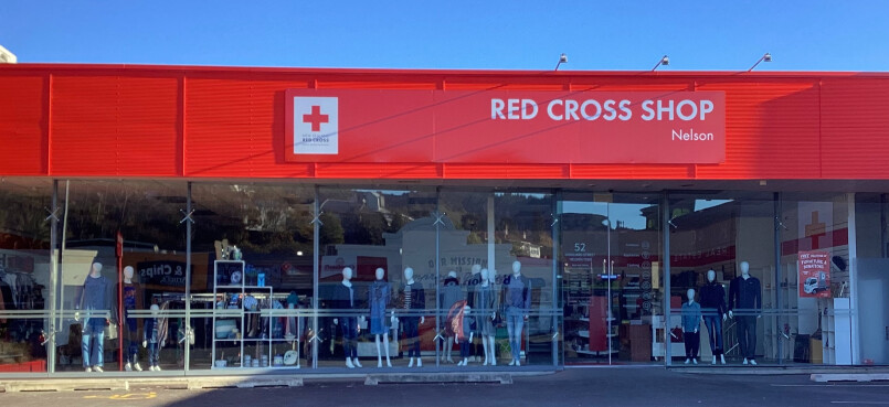 A large shop window showing dressed mannequins and a sign reading: Red Cross Shop Nelson