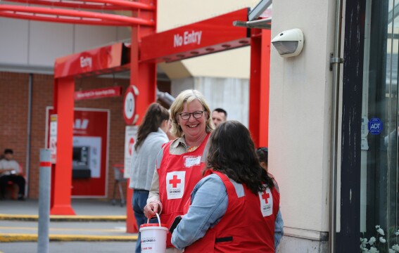 A woman smiling while wearing a fundraising bib and holding a donation bucket