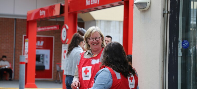 A woman smiling while wearing a fundraising bib and holding a donation bucket
