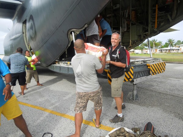 Two men lifting supplies from an aircraft cargo-hold. 