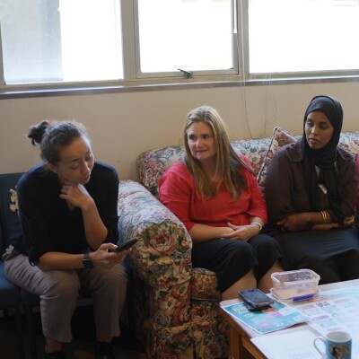 Three women are sitting on the couch and talking to each other
