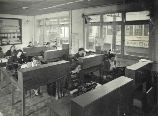 Women sitting and typing at desks in the 1940s.