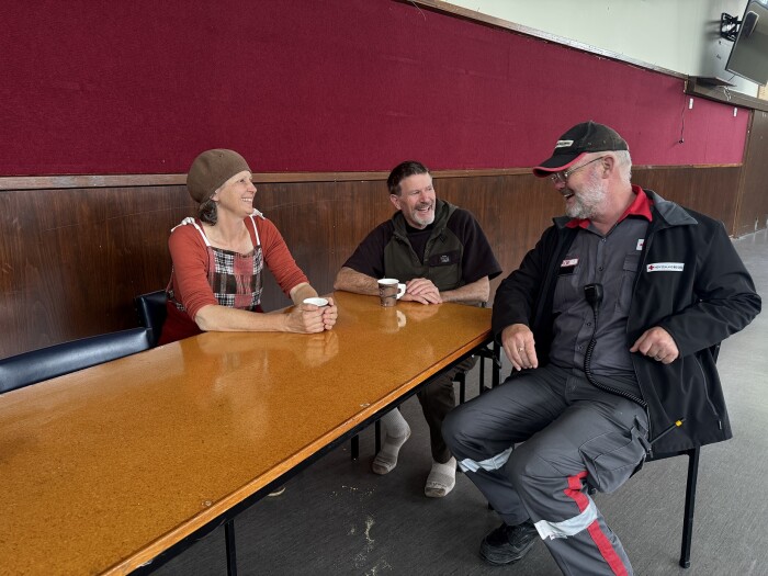 Three people talking at a table drinking coffee