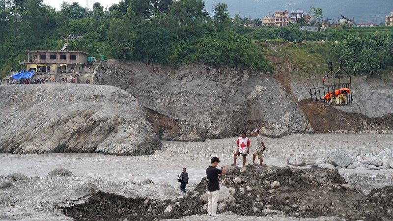 Nepal Red Cross volunteers operate a rope bridge across the river, pulling people two at a time across from the hospital on one side to the community on the other.