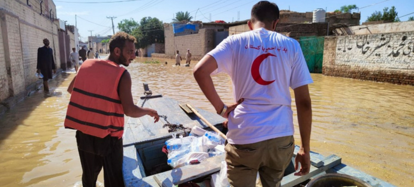 Two men with a boat of supplies in flood waters.