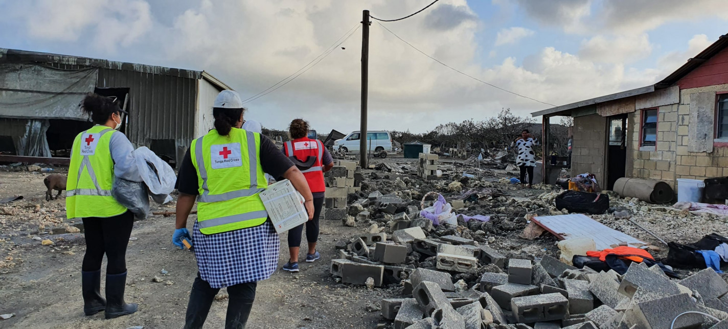People standing next to destroyed buildings.