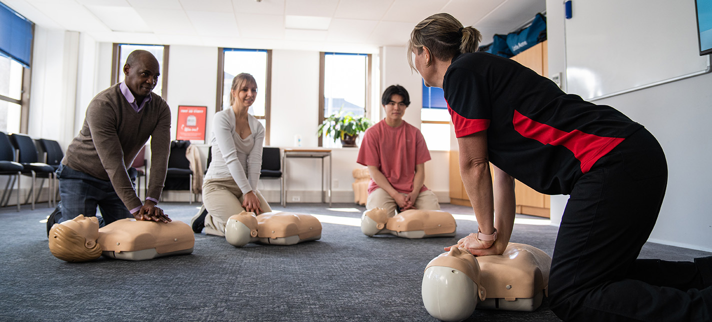 A volunteer demonstrates first aid to a group of students