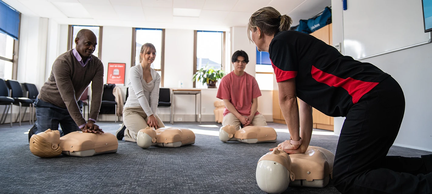 A volunteer demonstrates first aid to a group of students