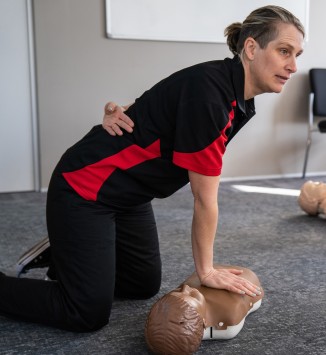 A volunteer demonstrates first aid on a mannequin
