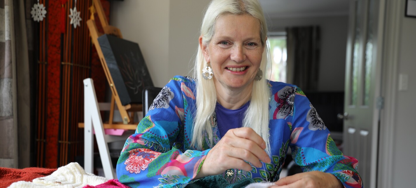 A woman looking at the camera while knitting.