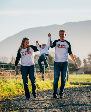 A man and woman lift a child into the air as they walk along a path together