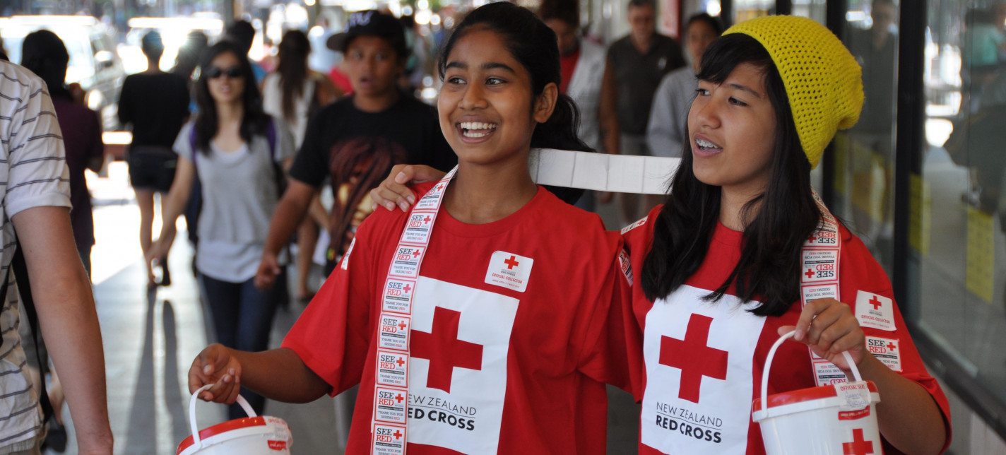 Two girls holding buckets and collecting donations for Red Cross