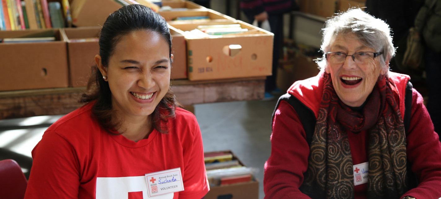 Two Red Cross volunteers sitting at a table laughing together